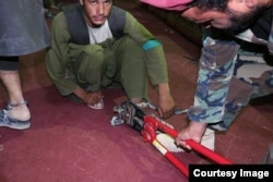 An Afghan army solider cuts chains of a prisoner freed from a Taliban prison in Helmand. (MOD)