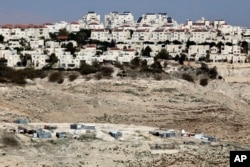 FILE - The Israeli settlement of Maaleh Adumim looms over Arab Bedouin shacks in the West Bank, Jan. 22, 2017.