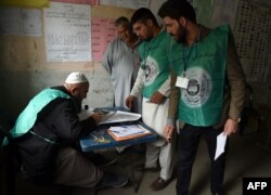 This photo taken on April 14, 2018, shows Afghan employees of the Independent Election Commission registering a resident at a voter registration center for the upcoming parliamentary and district council elections in Kabul.
