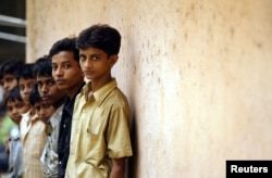 FILE - Indian child labourers rescued from different factories stand in a queue as a policeman (not pictured) records their names at a police station in Bombay in this June 1, 2005.