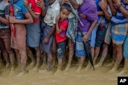 A young Rohingya Muslim boy, who crossed over from Myanmar into Bangladesh, waits alongwith others for his turn to collect food aid near Kutupalong refugee camp, Bangladesh, Sept. 19, 2017.