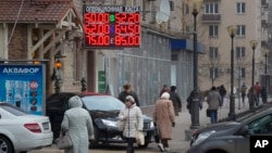 People walk past a currency exchange rate display in central Moscow, Dec. 1, 2014.