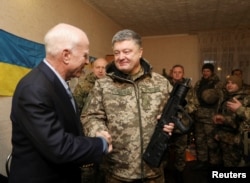Ukrainian President Petro Poroshenko (R) shakes hands with U.S. Senator John McCain during a meeting with Ukrainian servicemen in Shirokino settlement near Mariupol, Ukraine, Dec. 31, 2016.