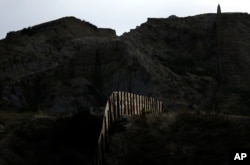 FILE - Light illuminates a section of the primary fence separating Tijuana, Mexico, and San Diego on June 22, 2016. An estimated 40 percent of the 11.4 million people in the U.S. illegally overstayed visas, a crucial but often overlooked fact in the immigration debate.