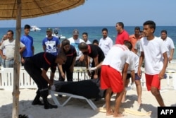 FILE - Tunisian lifeguards and medics transport a covered body in the resort town of Sousse, a popular tourist destination 140 kilometers (90 miles) south of the Tunisian capital, June 26, 2015.