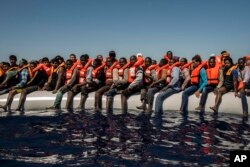 Refugees and migrants from Eritrea, Mali, Bangladesh and other countries wait on board a dinghy to be rescued in the Mediterranean Sea, 27 kilometers (17 miles) north of Sabratha, Libya, July 19, 2016.