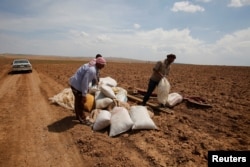 Iraqi farmers work in their fields north of Mosul, Iraq, May 2, 2018.