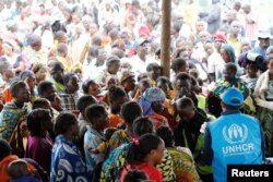 FILE - A U.N. worker monitors Congolese refugees upon arrival at a settlement camp in Kyangwali, Uganda, March 19, 2018.