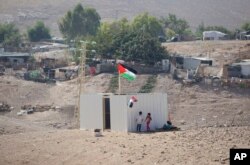 Palestinian girls sit by a newly made shed in the West Bank Bedouin community of Khan al-Ahmar, Sept. 11, 2018. Israel says Khan al-Ahmar was illegally built and has offered to resettle residents 12 kilometers (7 miles) away.