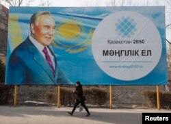A woman walks past a poster depicting Kazakhstan's President Nursultan Nazarbayev in Almaty, Feb. 16, 2015.