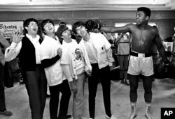 FILE - The Beatles, from left, Paul McCartney, John Lennon, Ringo Starr and George Harrison take a fake blow from Cassius Clay, who later changed his name to Muhammad Ali, while visiting the heavyweight contender in Miami Beach, Fla., Feb. 18, 1964.