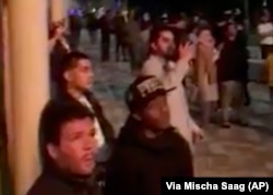 In this image made from video provided by Mischa Saag, onlookers watch a building on fire in London, Wednesday, June 14, 2017. Firefighters are battling a massive fire in an apartment high-rise in London.