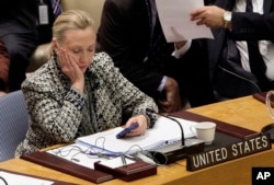 FILE - Then-Secretary of State Hillary Clinton checks her mobile phone after addressing the U.N. Security Council, March 12, 2012.