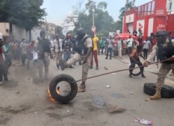 Police remove a burning tire as Haitians mount a nationwide strike to protest a growing wave of kidnappings, days after the abduction of a group of missionaries, in Port-au-Prince, Haiti, October 18, 2021.