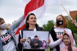 FILE - Belarus opposition leader Sviatlana Tsikhanouskaya holds a picture of her husband Syarhei Tsikhanouski during a "Belarus support day" protest in Vilnius, Lithuania, May 29, 2021.