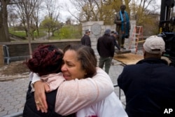 FILE - Dr. Bernadith Russell hugs a friend as the statue of Dr. J. Marion Sims, is removed from New York's Central Park, Apr. 7, 2018.