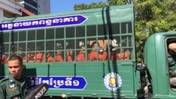 Prisoners wearing orange jumpsuits sit in a van en route from Prey Sar prison to the Phnom Penh Municipal Court, Cambodia, November 26, 2019. (Hul Reaksmey/VOA Khmer)