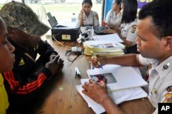 Relatives of passengers on the missing Trigana Air Service flight listen to a National Policies Disaster Victim Identification official at Sentani airport in Jayapura, Papua province, Indonesia, Aug. 17, 2015.