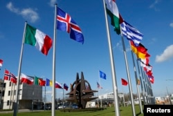 FILE - Flags fly at NATO headquarters in Brussels, Belgium, March 2, 2014. President Donald Trump has repeatedly asserted that member nations need to pay their fair share in defense spending.
