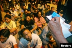 FILE - Indonesian migrant workers wait for Malaysian immigration officers to check their immigration status outside Kuala Lumpur.