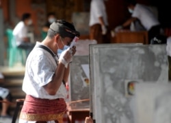 Seorang pria memegang surat suaranya dalam PIlkada di sebuah TPS di Denpasar, Bali, 9 Desember 2020. (Foto: SONNY TUMBELAKA / AFP)