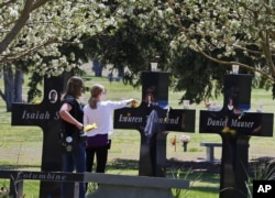 A family visits the memorial crosses dedicated to the students killed in the 1999 Columbine High School shooting attack