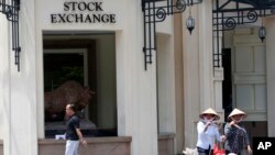 Warga melintas di depan Bursa Saham Hanoi, Vietnam.