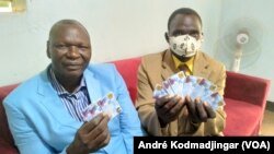 Dividi Boubar (à g.) et Natoïallah Ringar brandissent les doubles des cartes d'électeurs, à N’Djamena, au Tchad, le 7 avril 2021.