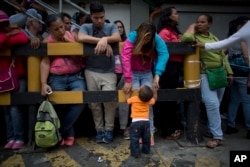 Madeley Vasquez, 16, stands with her one-year-old son Joangel outside a supermarket as she waits to buy food in Caracas, Venezuela, May 3, 2016.