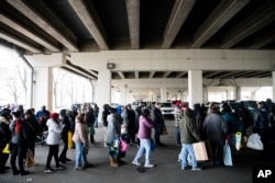 Furloughed federal workers and their families who are affected by the partial government shutdown wait in line to receive food distributed by Philabundance volunteers under Interstate 95 in Philadelphia, Jan. 23, 2019.