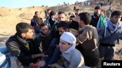 A wounded Palestinian protester is evacuated during clashes with Israeli troops as Palestinians call for a "day of rage" in response to U.S. President Donald Trump's recognition of Jerusalem as Israel's capital, near the border with Israel in the central