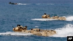 FILE - U.S. Navy amphibious assault vehicles with Philippine and U.S. troops on board are seen during joint exercises near a beach facing one of the contested islands in the South China Sea known as the Scarborough Shoal, April 21, 2015.