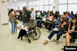 FILE - Larry Johnson (C) stands next his mother Ethel, 87, as they wait to get a voter ID card inside in Philadelphia, Sept. 27, 2012.