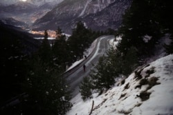 Afghan migrants Ali Rezaie and Sayed Hamza cross a mountain road in the French-Italian Alps to reach a migrant refuge in Briancon, France, Sunday, Dec. 12, 2021.