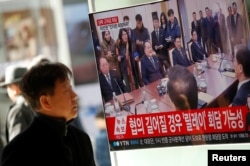 A man watches a TV broadcasting a news report on a high-level talks between the two Koreas at the truce village of Panmunjom, in Seoul, South Korea, Jan. 9, 2018.
