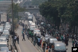 Ribuan pelayat berjajar di tepi jalan untuk menyaksikan iring-iringan kendaraan yang membawa jenazah Habibie ke Taman Makam Pahlawan Kalibata, Jakarta Selatan, hari Kamis (12/9).