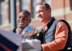 Denver Broncos quarterback Peyton Manning and defensive end DeMarcus Ware hold the Lombardi Trophy during a parade for the NFL football Super Bowl champions in Denver, Feb. 9, 2016.
