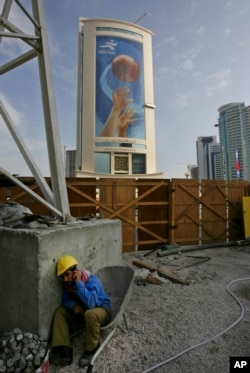 FILE - A construction worker takes time off to call a friend in Doha, Qatar, Nov. 30, 2006. Like other energy-rich Gulf nations, Qatar relies heavily on migrant workers drawn mainly from South Asia to build its roads, skyscrapers and stadiums.