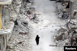 FILE - A woman walks past damaged buildings in the rebel-controlled area of Maaret al-Numan town in Idlib province, Syria, May 13, 2016.