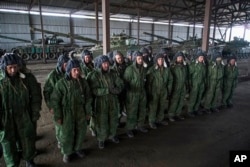 FILE - Russia-backed rebels are seen lined up in front of tanks near Novoazovsk, eastern Ukraine, Oct. 21, 2015.