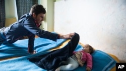 Shaker Mahie, 24, covers his 10-month-old daughter, Maria, inside the room of a hotel in the northern Greek village of Agios Athanasios, Dec. 21, 2017. As a member of a persecuted minority in Iraq, Shaker Mahie has seen his people massacred, raped and scattered.