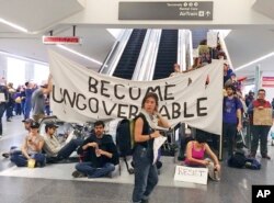 Demonstrators block an escalator at the international terminal in protest of President Donald Trump's executive order banning travel from seven Muslim-majority countries at San Francisco International Airport, Jan. 29, 2017.