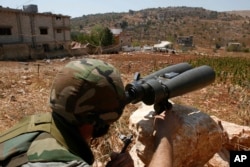 FILE - A Hezbollah fighter uses binoculars to scan for Israeli forces' positions, on the outskirts of the village of Aitaroun, near the town of Bint Jbeil, Aug. 16, 2006. With Trump's rise to power, many members of the Shi'ite community in Lebanon are increasingly uneasy about the future.