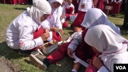 Students trained in first aid assist a classmate during a mock earthquake drill in Central Java, Indonesia, October 22, 2012. (S. Schonhardt/VOA)