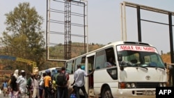Quelqeus personnes attendet en queue pour embarquer dans un bus garé à Akanyaru du côté rwandais de la rue située à la frontière avec le Burundi, le 23 août 2016.