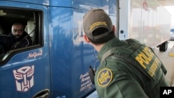 FILE - Border Patrol agent Eric Mendoza speaks to the driver of a tractor-trailer waiting to pass through the Laredo North vehicle checkpoint in Laredo, Texas, on Feb. 2, 2018.