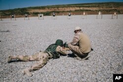 FILE - A Dutch army trainer, right, helps a Kurdish peshmerga soldier during a military training session at a shooting range, at Bnaslawa Military Base in Irbil, northern Iraq, March 9, 2016.