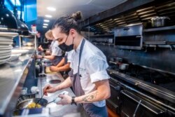 FILE - Sebastian Cacho cooks in the kitchen at Gotham restaurant on Dec. 14, 2021, in New York.