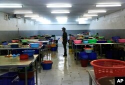A Thai soldier stands between abandoned work stations during a raid on a shrimp shed in Samut Sakhon, Thailand, Nov. 9, 2015.