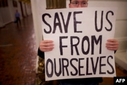 FILE - A Donald Trump protester joins demonstrators inside the Pennsylvania Capitol Building before electors arrive to cast their votes from the election in Harrisburg, Pennsylvania, Dec. 19, 2016.